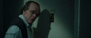 Movie still from “Synecdoche, New York” (2008), directed by Charlie Kaufman – A man in glasses and a tie standing in front of a door; Close Up shot, Low angle
