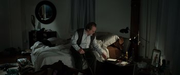 Movie still from “Synecdoche, New York” (2008), directed by Charlie Kaufman – A man sitting on a bed in a dark room; Wide shot, High angle