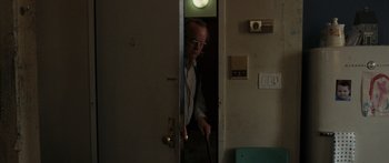 Movie still from “Synecdoche, New York” (2008), directed by Charlie Kaufman – An older man holding a cane in front of an open door; Medium shot, High angle
