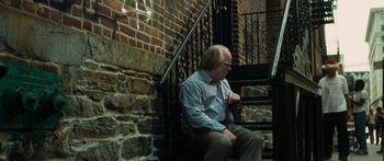 Movie still from “Synecdoche, New York” (2008), directed by Charlie Kaufman – An older man sitting on a bench next to a staircase; Medium shot, High angle