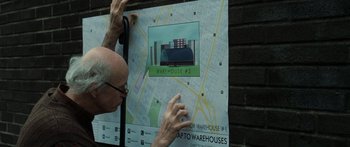 Movie still from “Synecdoche, New York” (2008), directed by Charlie Kaufman – An older man putting up a map on a wall; Close Up shot, High angle