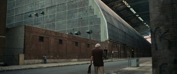 Movie still from “Synecdoche, New York” (2008), directed by Charlie Kaufman – An older man walking down the street in front of a building; Extreme Wide shot, High angle