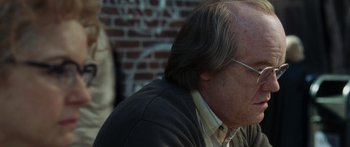 Movie still from “Synecdoche, New York” (2008), directed by Charlie Kaufman – An older man with long grey hair wearing glasses and a sweater; Close Up shot, Over the shoulder angle
