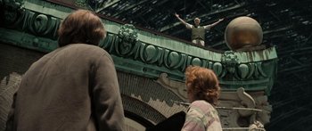 Movie still from “Synecdoche, New York” (2008), directed by Charlie Kaufman – A man standing on top of a building with his arms outstretched; Wide shot, Low angle