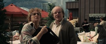Movie still from “Synecdoche, New York” (2008), directed by Charlie Kaufman – An older man standing next to an older woman; Medium shot, High angle