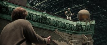 Movie still from “Synecdoche, New York” (2008), directed by Charlie Kaufman – A man standing on top of a building near a hand; Wide shot, Low angle