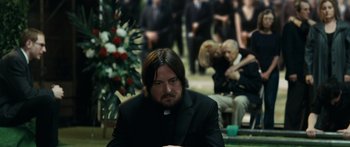 Movie still from “Synecdoche, New York” (2008), directed by Charlie Kaufman – A priest sitting in front of a bunch of people; Medium shot, Over the shoulder angle