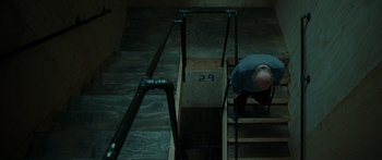 Movie still from “Synecdoche, New York” (2008), directed by Charlie Kaufman – A man walking up some stairs in the dark; Wide shot, Overhead angle
