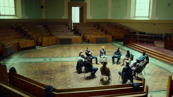 Movie still from “T2 Trainspotting” (2017), directed by Danny Boyle – A group of people sitting on chairs in a room; Extreme Wide shot, High angle