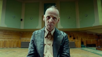 Movie still from “T2 Trainspotting” (2017), directed by Danny Boyle – A man with a shaved head wearing a leather jacket and tie; Close Up shot, Low angle