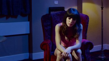 Movie still from “T2 Trainspotting” (2017), directed by Danny Boyle – A woman sitting on a chair in a room; Medium shot, High angle