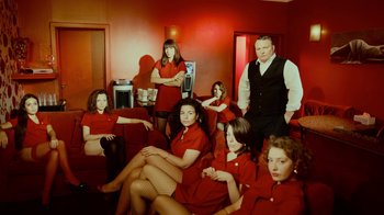 Movie still from “T2 Trainspotting” (2017), directed by Danny Boyle – A group of women and a man sitting on couches in a living room; Wide shot, Low angle