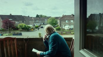 Movie still from “T2 Trainspotting” (2017), directed by Danny Boyle – A woman sitting on a chair with a cup of coffee; Wide shot, Over the shoulder angle