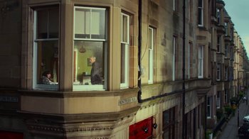 Movie still from “T2 Trainspotting” (2017), directed by Danny Boyle – A man standing on a window ledge looking out of a window; Extreme Wide shot, High angle