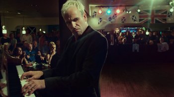 Movie still from “T2 Trainspotting” (2017), directed by Danny Boyle – A man with white hair is standing in front of a crowd; Medium shot, Low angle
