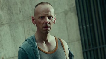 Movie still from “T2 Trainspotting” (2017), directed by Danny Boyle – A man with a shaved head wearing a tank top; Close Up shot, Low angle