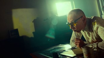 Movie still from “T2 Trainspotting” (2017), directed by Danny Boyle – A man sitting at a table with a pen in his mouth; Medium shot, Low angle