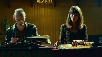 Movie still from “T2 Trainspotting” (2017), directed by Danny Boyle – A man and a woman sitting at a table with papers; Medium shot, Low angle