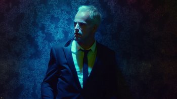 Movie still from “T2 Trainspotting” (2017), directed by Danny Boyle – A man wearing a suit and tie smoking a cigarette; Close Up shot, Low angle