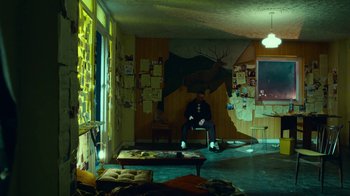 Movie still from “T2 Trainspotting” (2017), directed by Danny Boyle – A man sitting on a chair in a living room; Wide shot, High angle