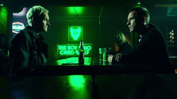 Movie still from “T2 Trainspotting” (2017), directed by Danny Boyle – Two men sitting at a table in front of a neon sign; Medium shot, Over the shoulder angle