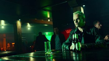 Movie still from “T2 Trainspotting” (2017), directed by Danny Boyle – A man sitting at a table with a bottle of beer; Close Up shot, Low angle