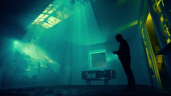 Movie still from “T2 Trainspotting” (2017), directed by Danny Boyle – A man standing in front of a television in a dark room; Extreme Wide shot, Low angle