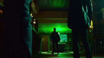 Movie still from “T2 Trainspotting” (2017), directed by Danny Boyle – A man standing in a dark room with green lights; Wide shot, Low angle