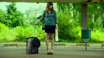 Movie still from “T2 Trainspotting” (2017), directed by Danny Boyle – A woman standing next to a suitcase on the sidewalk; Wide shot, Low angle