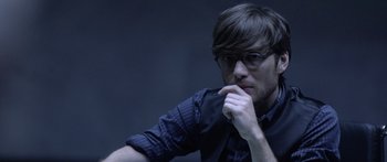 Movie still from “TRON: Legacy” (2010), directed by Joseph Kosinski – A man with glasses is sitting down; Close Up shot, Over the shoulder angle