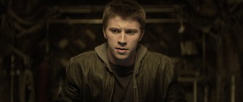 Movie still from “TRON: Legacy” (2010), directed by Joseph Kosinski – A young man in a brown jacket looking at the camera; Close Up shot, High angle