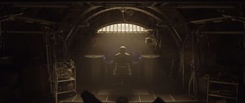 Movie still from “TRON: Legacy” (2010), directed by Joseph Kosinski – A man sitting in a chair in front of an open window; Wide shot, Low angle