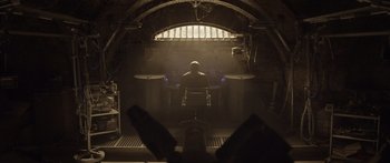 Movie still from “TRON: Legacy” (2010), directed by Joseph Kosinski – A man sitting in a chair in front of a window; Wide shot, Low angle