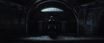 Movie still from “TRON: Legacy” (2010), directed by Joseph Kosinski – A man sitting in a chair in a dark room; Wide shot, High angle