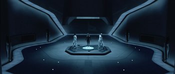 Movie still from “TRON: Legacy” (2010), directed by Joseph Kosinski – A group of people standing on a platform in a dark room; Wide shot, High angle
