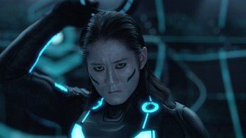 Movie still from “TRON: Legacy” (2010), directed by Joseph Kosinski – A woman in a tron costume looking into the camera; Close Up shot, Low angle