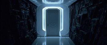 Movie still from “TRON: Legacy” (2010), directed by Joseph Kosinski – A white door in a room that has a light on it; Wide shot, Overhead angle