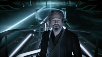 Movie still from “TRON: Legacy” (2010), directed by Joseph Kosinski – An older man in a black jacket and a gray tie; Close Up shot, Over the shoulder angle