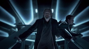 Movie still from “TRON: Legacy” (2010), directed by Joseph Kosinski – An older man standing in a dark room with his arms outstreched; Medium shot, Over the shoulder angle