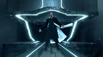 Movie still from “TRON: Legacy” (2010), directed by Joseph Kosinski – A man in a suit and tie standing in an illuminated room; Wide shot, Low angle