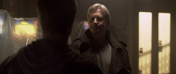 Movie still from “TRON: Legacy” (2010), directed by Joseph Kosinski – An older man wearing glasses and a brown jacket; Close Up shot, Over the shoulder angle