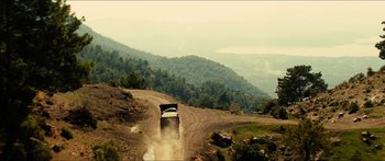 Movie still from “Taken 2” (2012), directed by Olivier Megaton – A truck driving down a dirt road near a forest; Extreme Wide shot, High angle