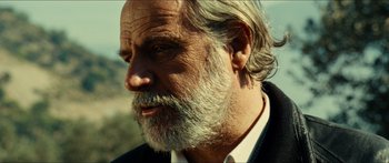 Movie still from “Taken 2” (2012), directed by Olivier Megaton – An older man with a beard and a white shirt; Close Up shot, Over the shoulder angle