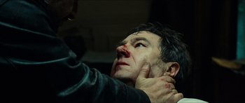 Movie still from “Taken 2” (2012), directed by Olivier Megaton – A man with bruises on his face and neck; Close Up shot, Over the shoulder angle