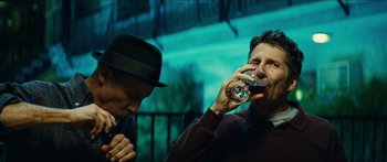 Movie still from “Taken 2” (2012), directed by Olivier Megaton – Two men are drinking wine in front of a fence; Close Up shot, Low angle