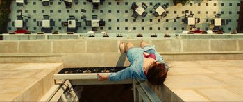 Movie still from “Taken 2” (2012), directed by Olivier Megaton – A person laying on the ground on a ledge; Wide shot, Overhead angle