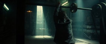 Movie still from “Taken 2” (2012), directed by Olivier Megaton – A person holding a weight in a room; Wide shot, Low angle