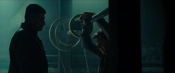 Movie still from “Taken 2” (2012), directed by Olivier Megaton – A man holding a large metal object in a dark room; Medium shot, Low angle