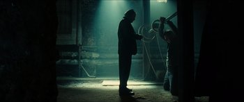 Movie still from “Taken 2” (2012), directed by Olivier Megaton – A man standing next to another man in a dark room; Wide shot, Low angle
