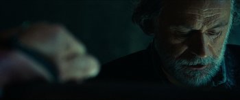 Movie still from “Taken 2” (2012), directed by Olivier Megaton – A man in a black suit is sitting in a dark room; Close Up shot, Over the shoulder angle